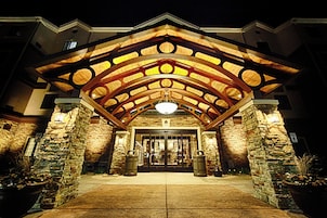 Fachada de hotel de piedra, arco de madera y una puerta grande.