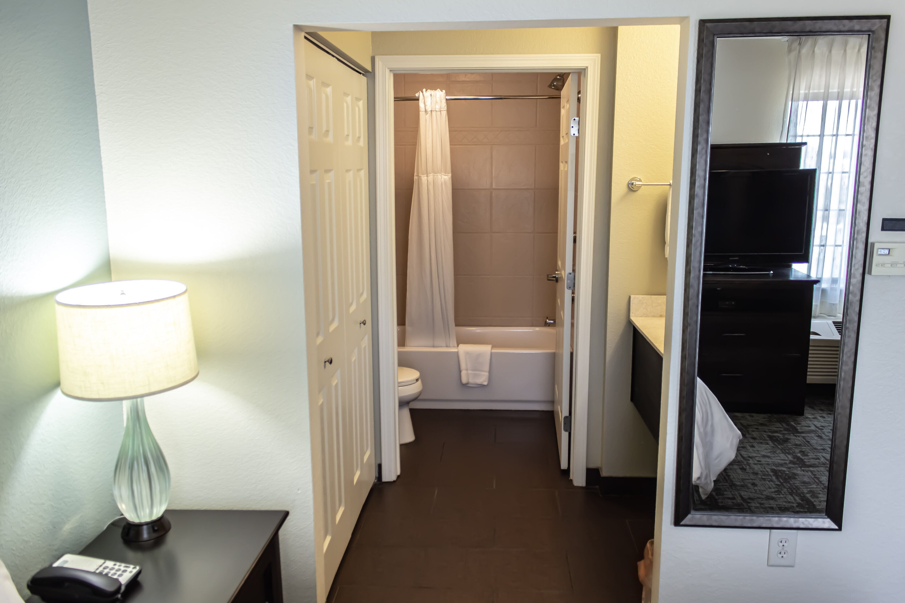 A bathroom with a toilet, bathtub, and a mirror.