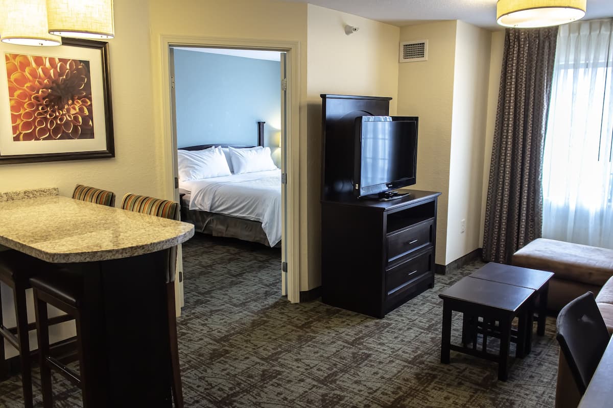Habitación de hotel con cama, televisión, escritorio y zona de bar.