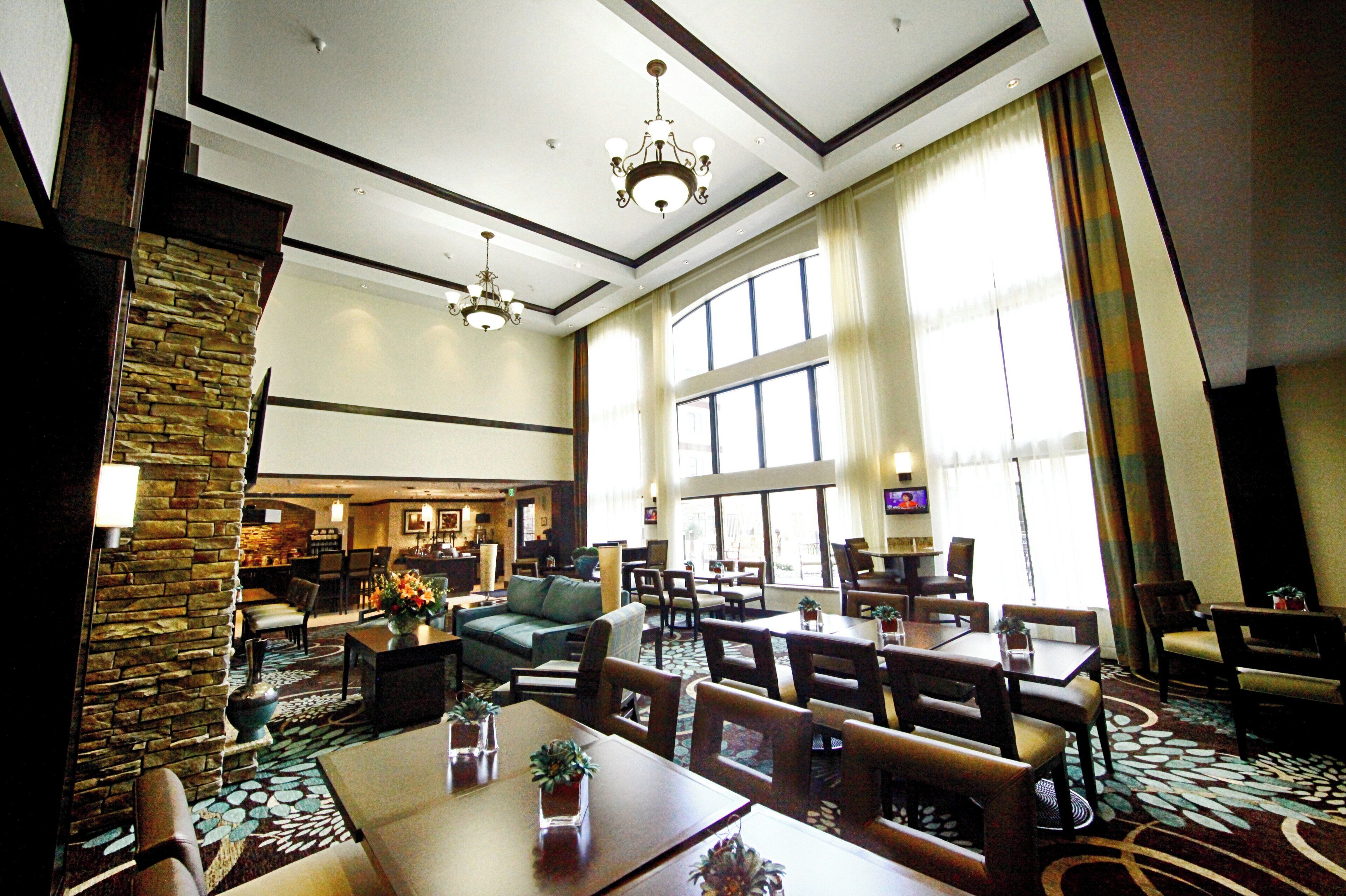 A hotel lobby with a fireplace, seating area, and large windows.