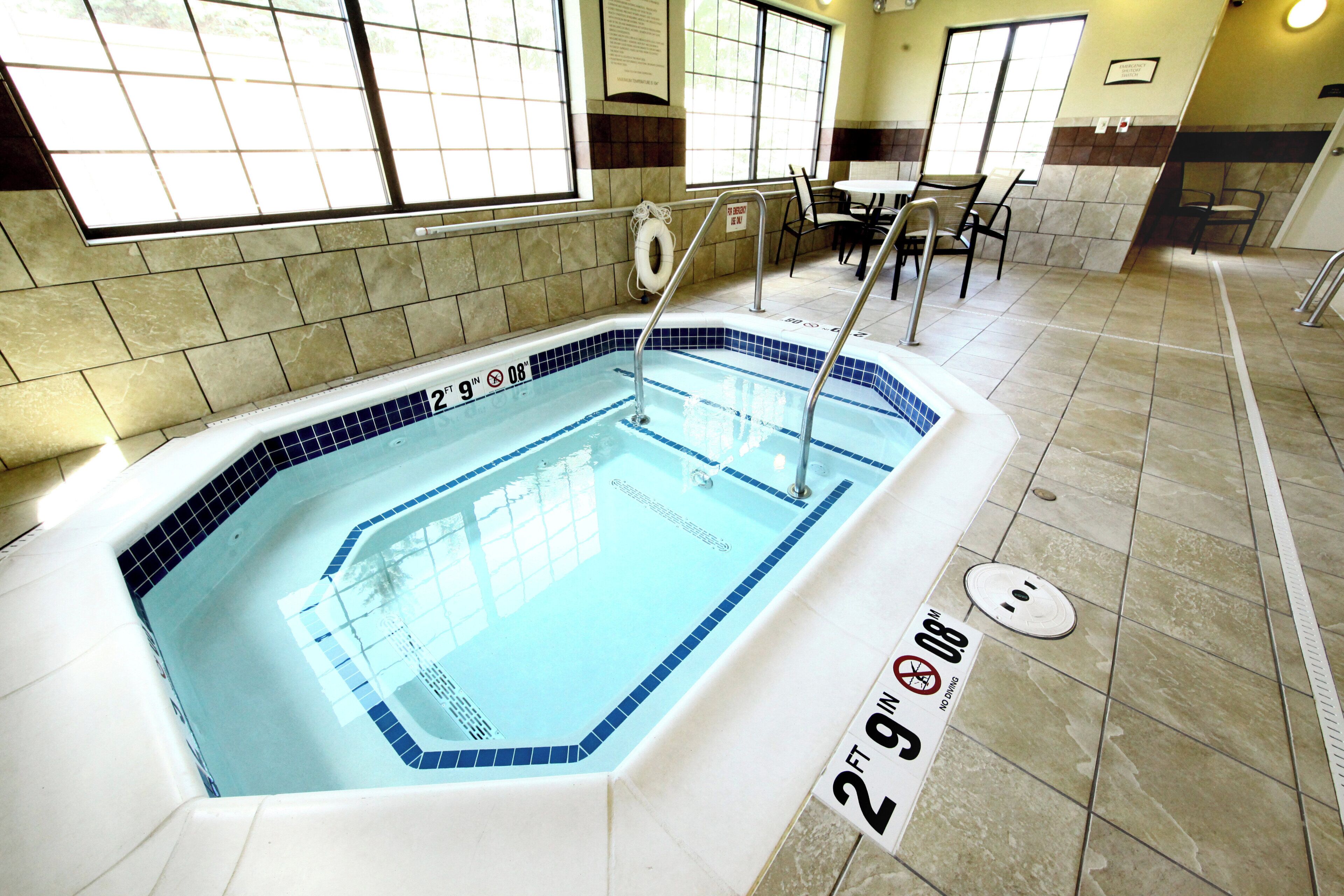 Une piscine intérieure à l’eau claire, entourée de murs et d’un sol recouverts de carreaux.