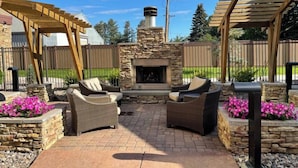An outdoor patio with stone walls, a stone fireplace, and wicker furniture.