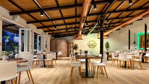 A spacious dining area with wooden tables and white chairs, featuring a modern ceiling with exposed beams and copper pipes. - Wyndham Residences Golf del Sur (San Miguel de Abona)