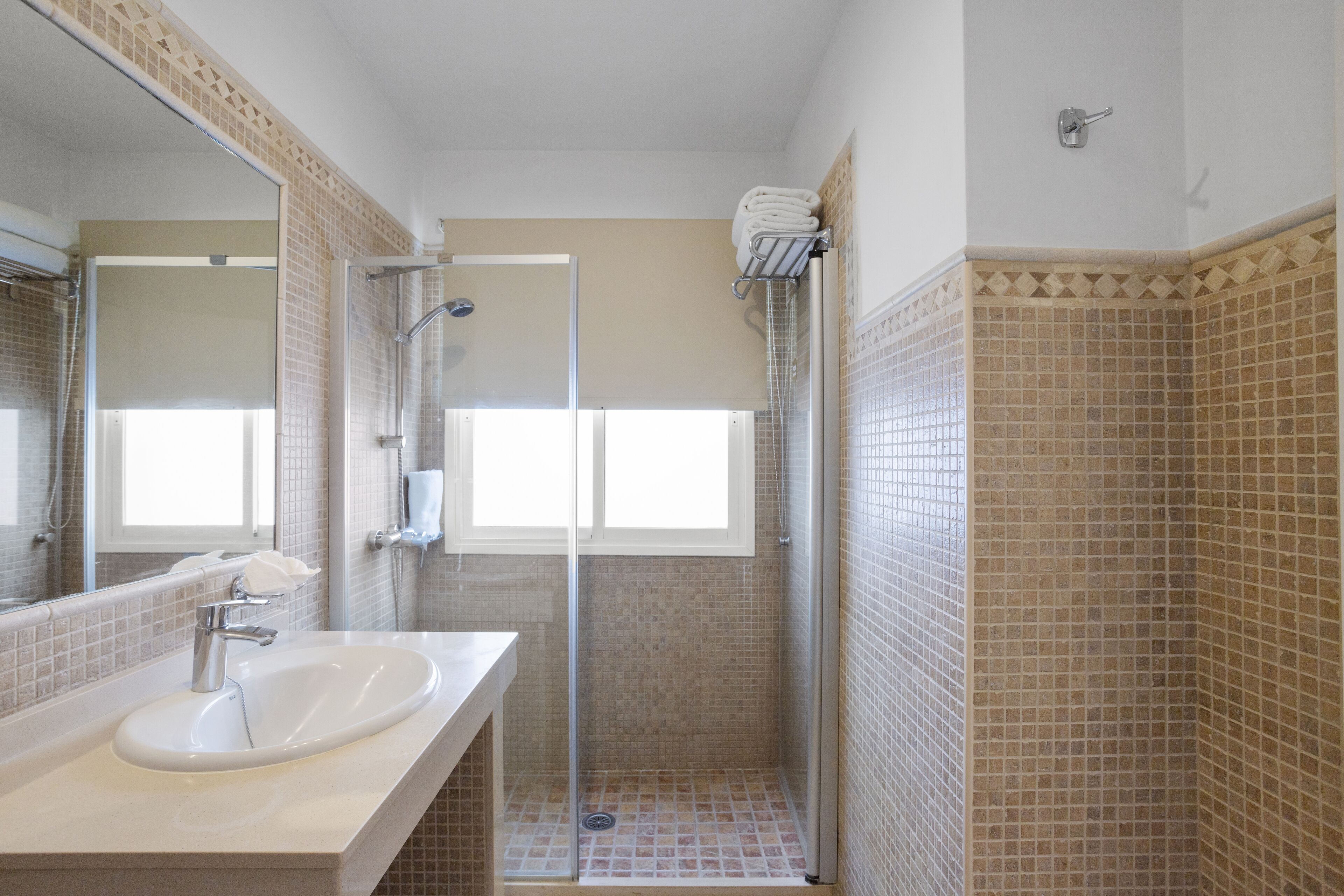 Une salle de bain avec un lavabo, un miroir, une douche et des murs carrelés.