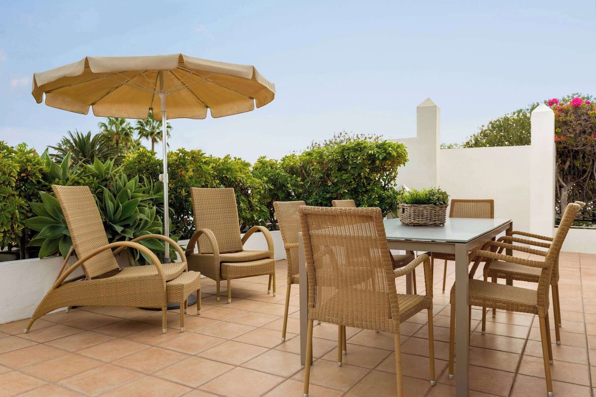 A patio with wicker furniture, a table, and an umbrella.
