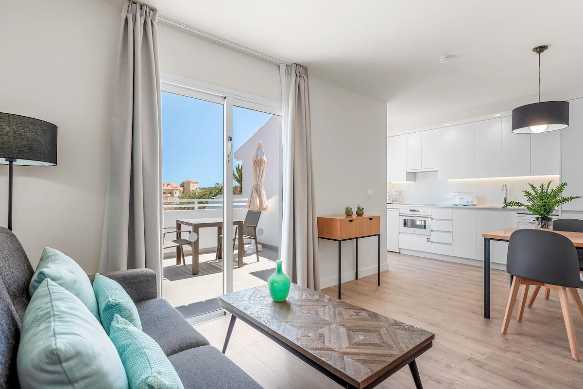 A modern apartment with a living room, dining area, and kitchen.