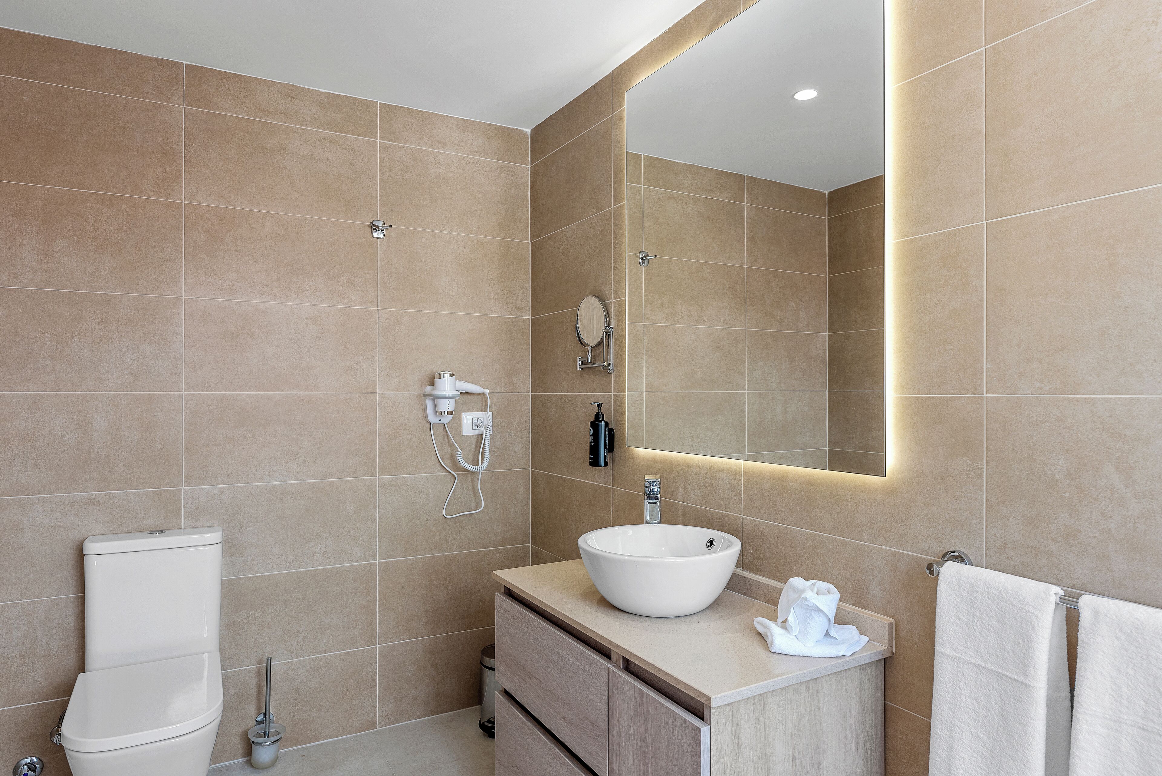 Een moderne badkamer met toilet, wastafel en spiegel.