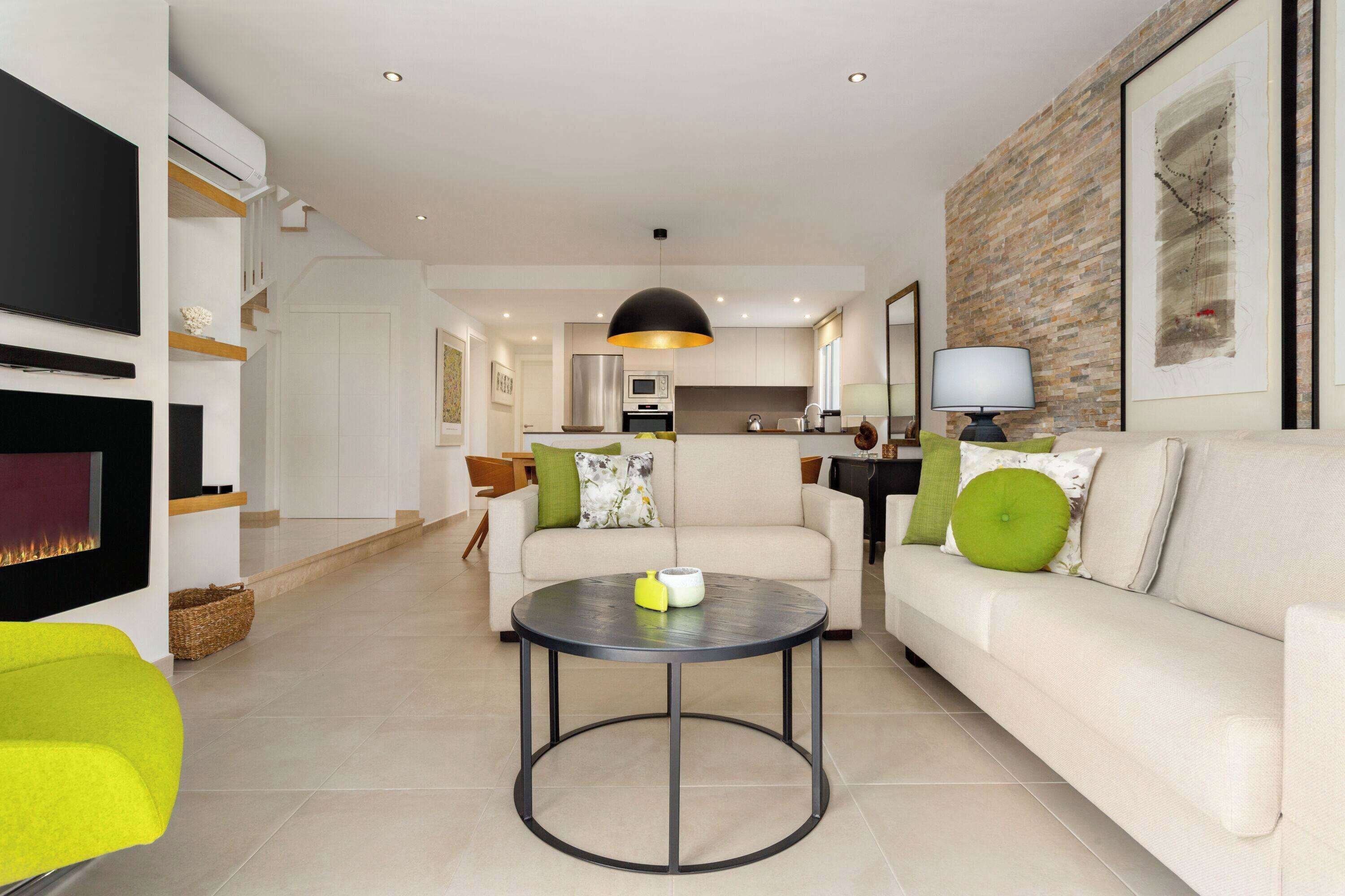 A modern living room with a fireplace, a round coffee table, and a sofa with green cushions.