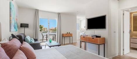 Een moderne hotelkamer met een groot bed, een bureau, een flatscreen-tv en een balkon met uitzicht.