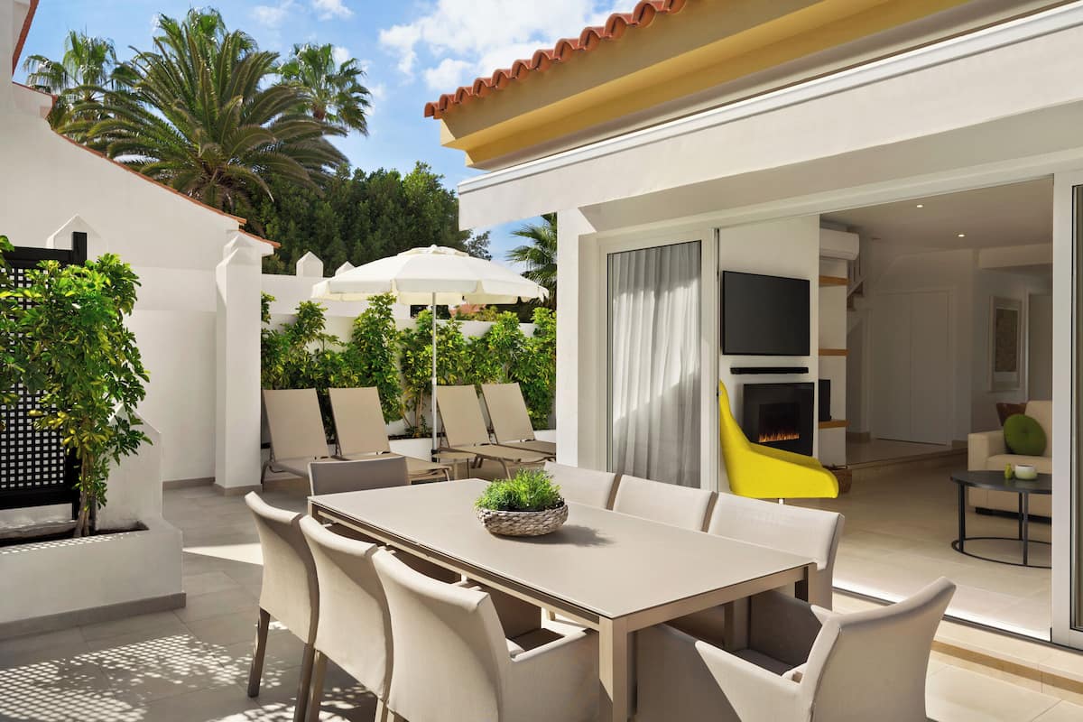 An outdoor patio with a dining table, chairs, and umbrellas.