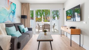 A modern living room with a grey sofa, teal cushions, a coffee table, and a TV on the wall. - Wyndham Residences Golf del Sur (San Miguel de Abona)