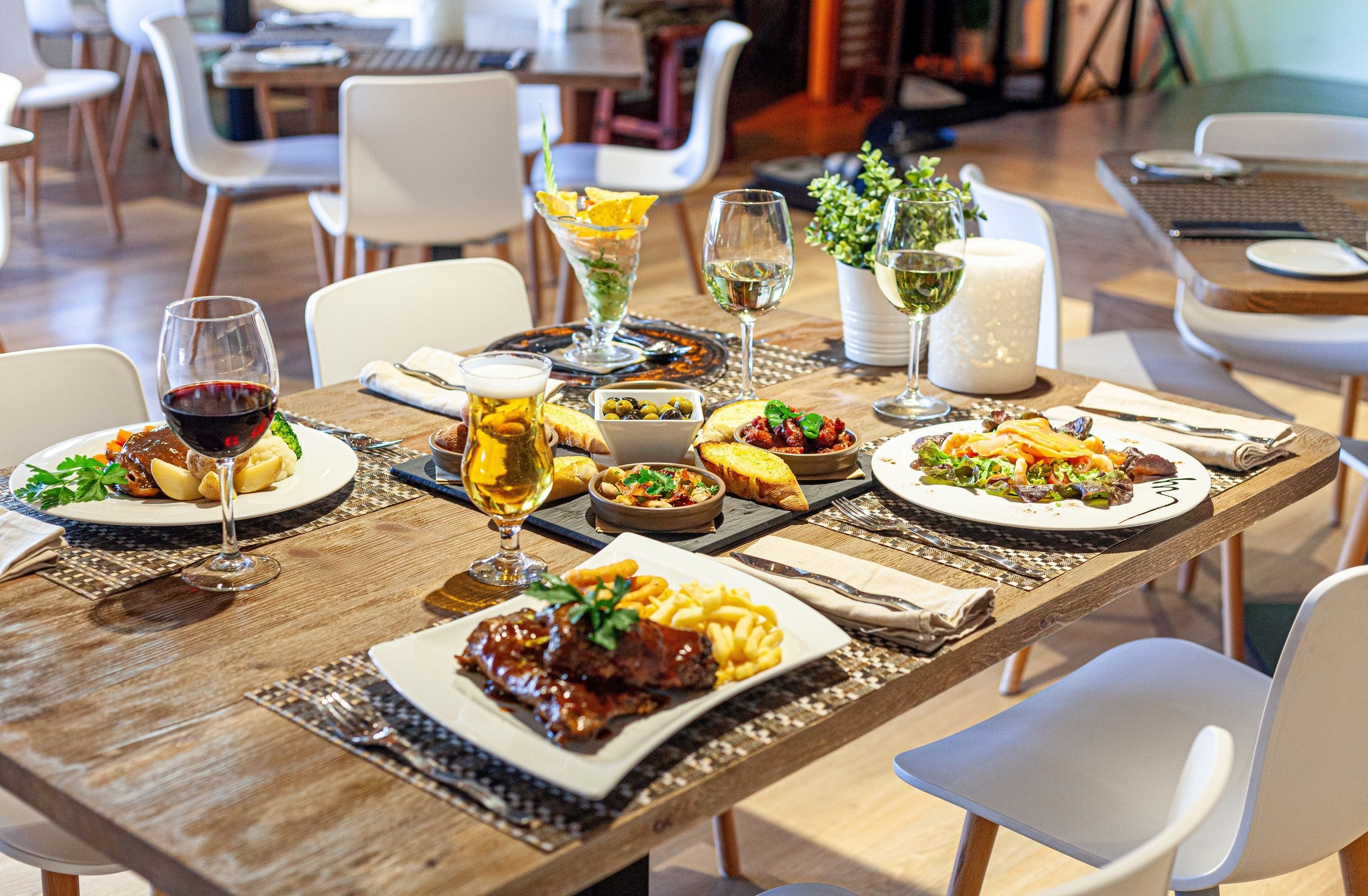 A dining table set with various dishes, wine glasses, and a potted plant.