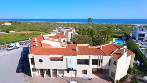 A multi-story building with a red-tiled roof, a swimming pool, and a view of the sea. - Praia da Lota Resort - Hotel (Vila Real Santo Antonio)
