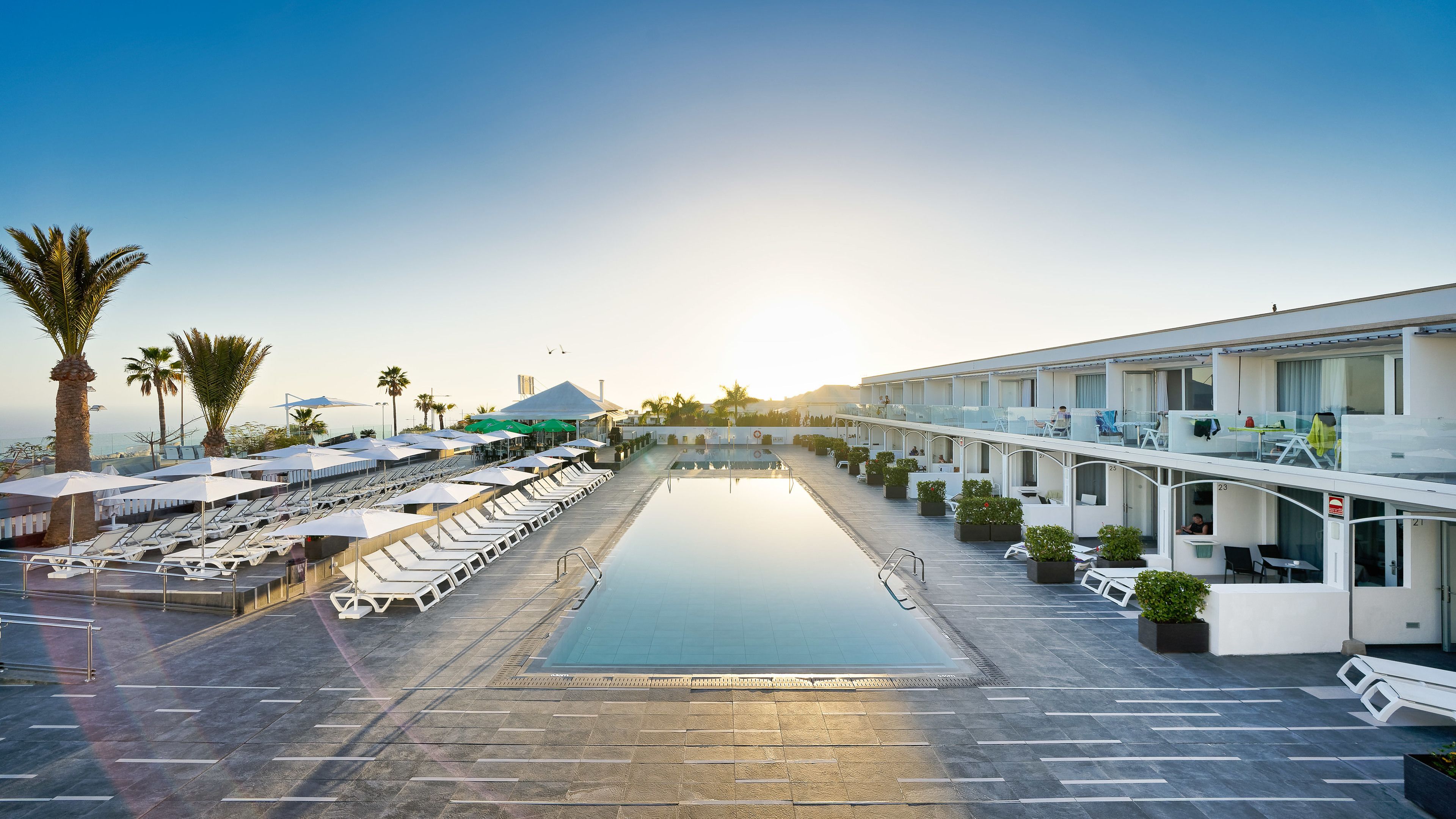 Un hôtel doté d’une piscine, de chaises longues et d’un espace extérieur couvert.