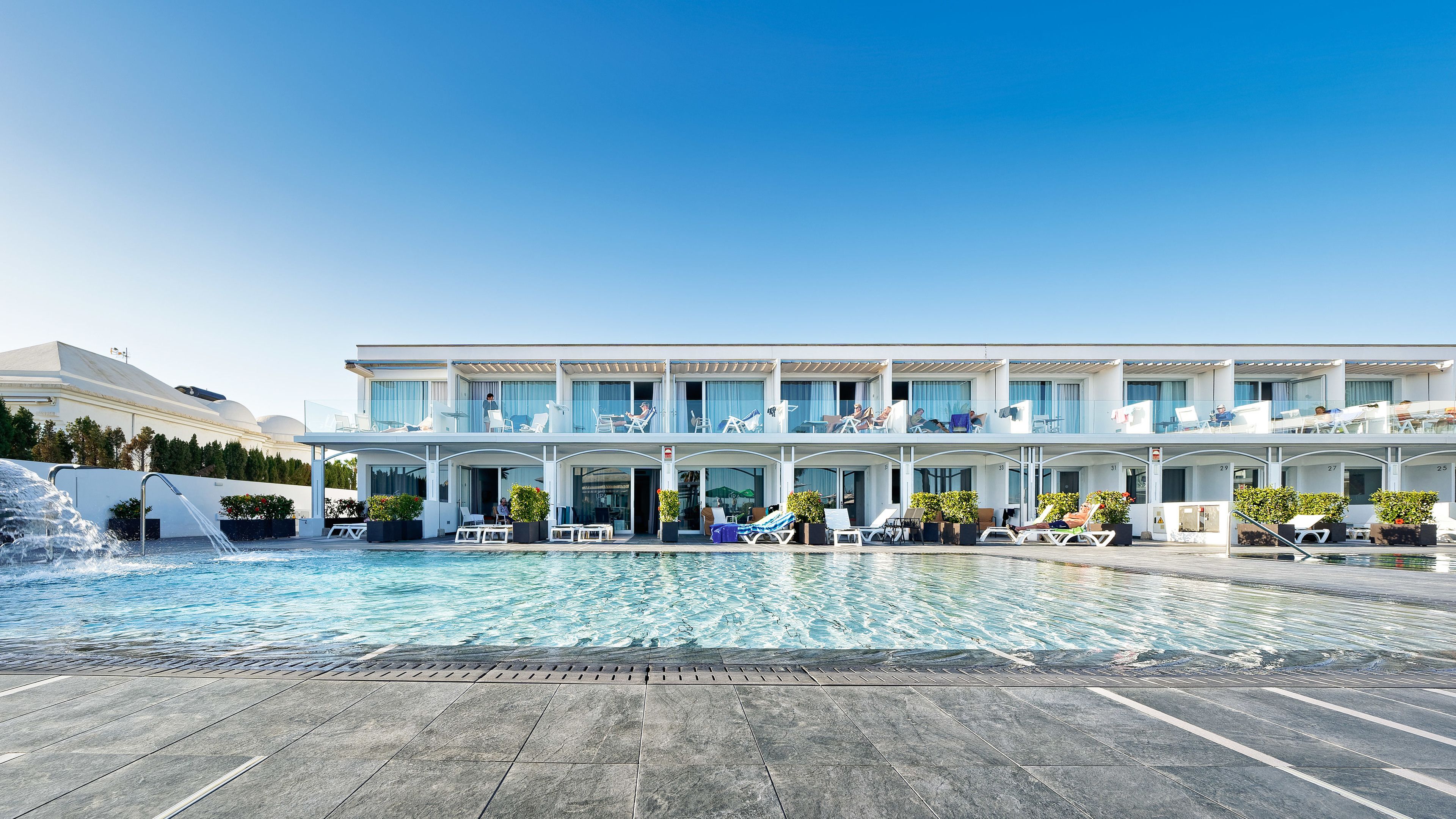 Un hôtel moderne doté d’une piscine, de nombreux balcons et d’espaces de détente en plein air.