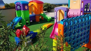 Un espace de jeux pour enfants avec différentes structures en plastique colorées et un toboggan.
