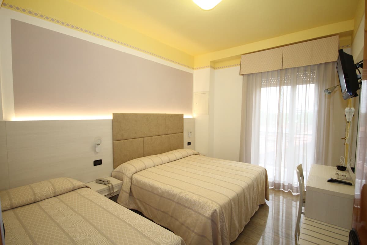 Ein Hotelzimmer mit zwei Betten, einem Schreibtisch und einem Fernseher.