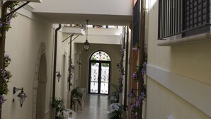 A multi-level interior with a central open corridor, decorative railings, and potted plants. - Palazzo Reginella Residence Hotel (Bovalino)