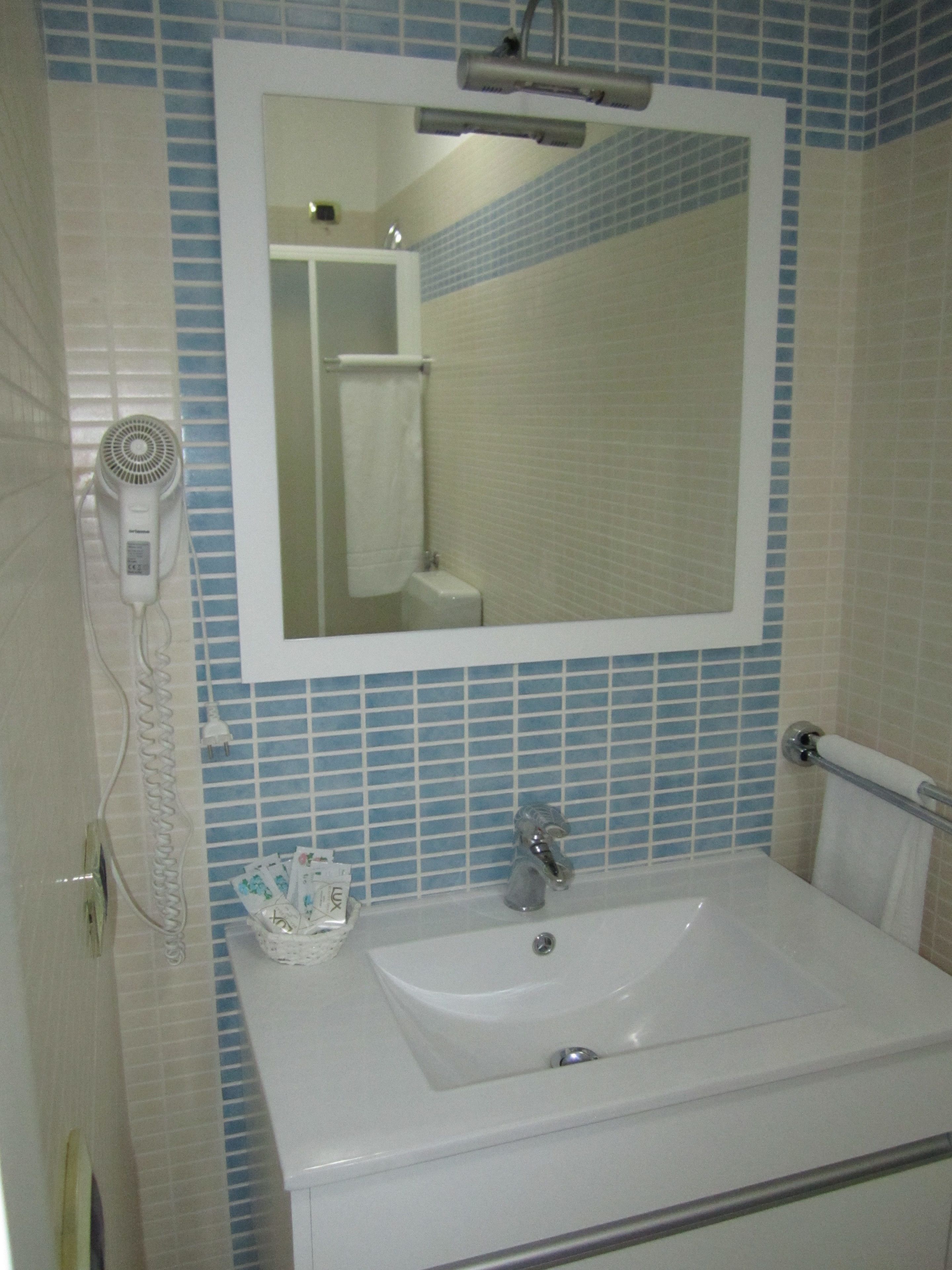A bathroom with a white sink, a mirror, and a blue-tiled wall.