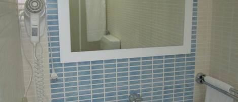 A bathroom with a white sink, a mirror, and a blue-tiled wall.