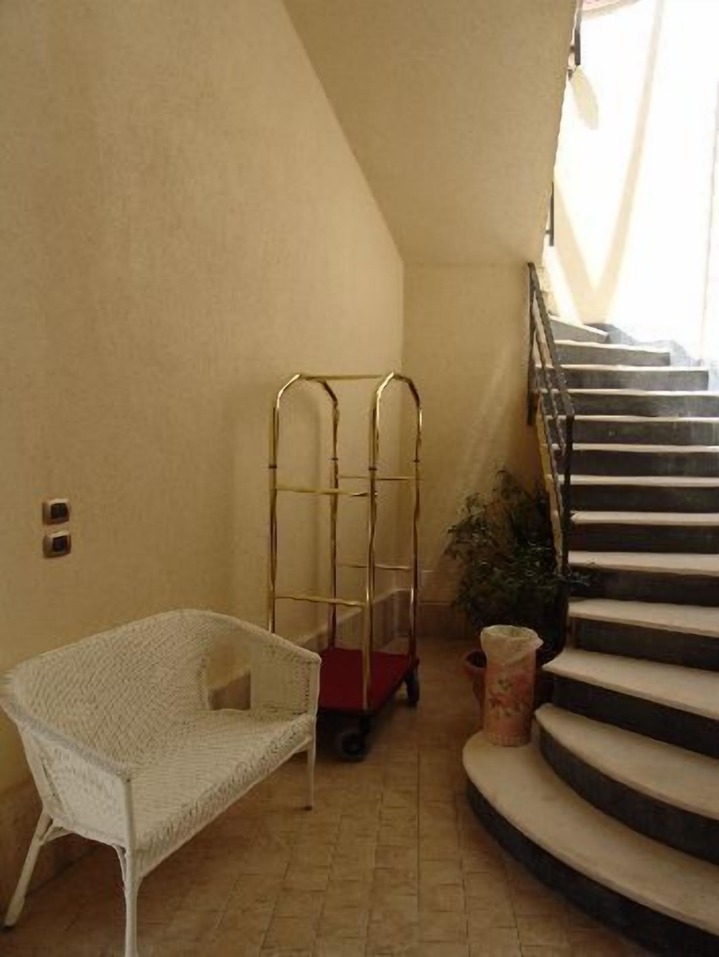 Eine Treppe mit Handlauf, ein weißer Korbstuhl und ein Metallwagen.
