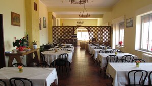 Un restaurante con varias mesas y sillas, suelo de madera y un separador decorativo de celosía al fondo.