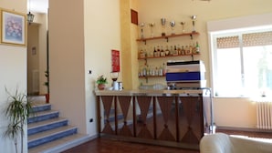 Una zona de bar con estantes llenos de botellas, una máquina de café y una barra.