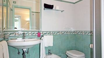 Ein Badezimmer mit Waschbecken, zwei Toiletten, einer Dusche und einem Spiegel.