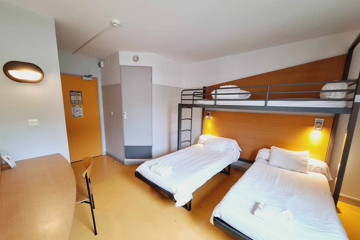 A hotel room with bunk beds, a desk, and a chair.