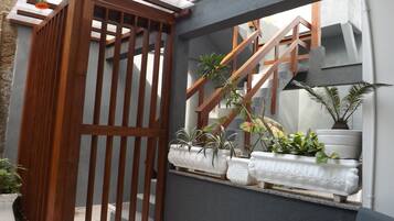 Um espaço ao ar livre moderno com portão de madeira, parede de concreto e plantas em vasos.