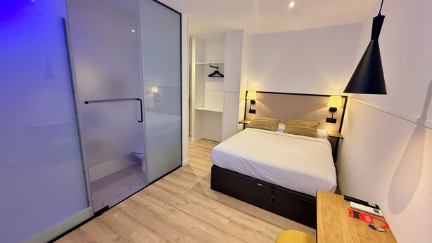 A modern bedroom with a bed, bedside table, and a small desk.