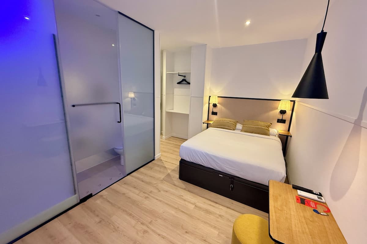 A modern bedroom with a bed, bedside table, and a small desk.