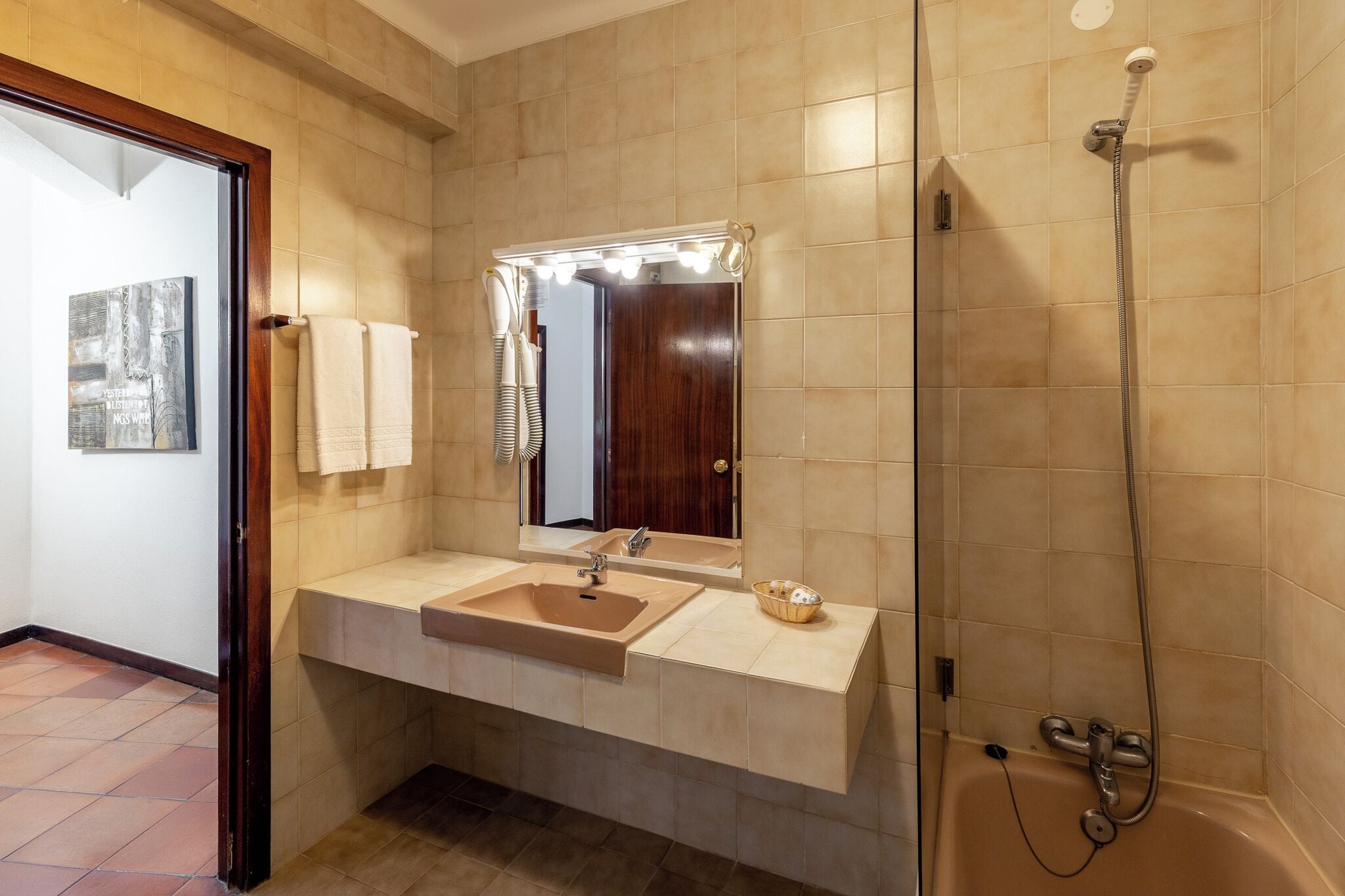 A bathroom with a sink, mirror, vanity, and shower.