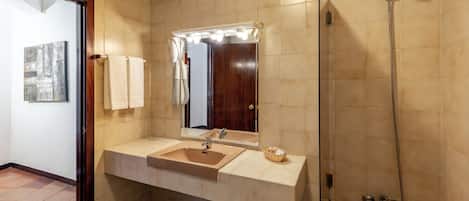 Ein Badezimmer mit Waschbecken, Spiegel, Waschtisch und Dusche.