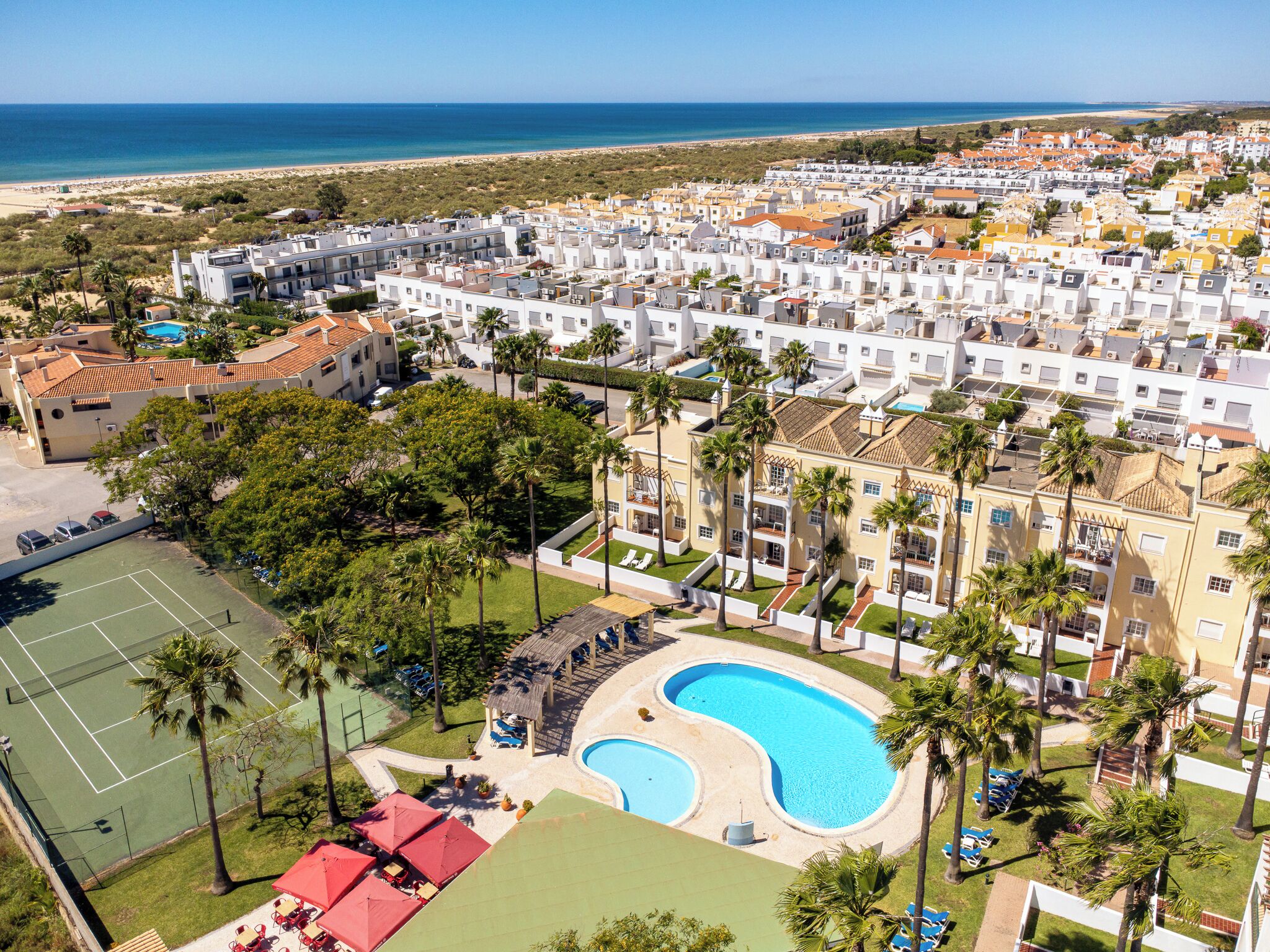 Zona residencial con piscina, cancha de tenis y vista a la playa.