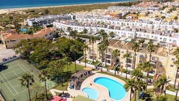 Zona residencial con piscina, cancha de tenis y vista a la playa.