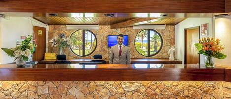 Un comptoir d’accueil avec une façade en pierre, un lambris en bois et un écran de télévision.