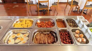 A buffet with various food options including eggs, bacon, beans, and other dishes.