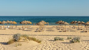 A beach with sun loungers and thatched umbrellas, a sandy beach, and the ocean. - Praia da Lota Resort – Hotel & Apartments (Vila Real Santo Antonio)