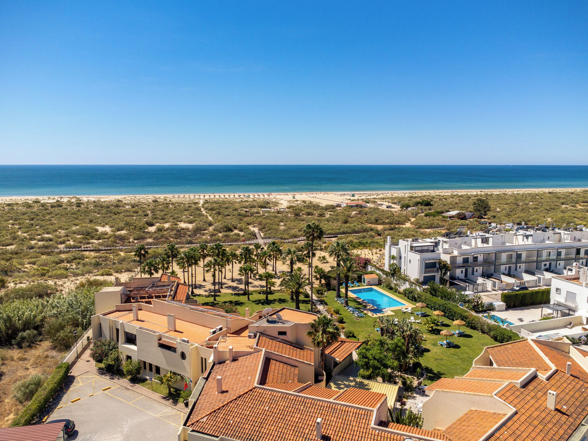 Un resort con piscina, vistas a la playa y varias edificaciones.
