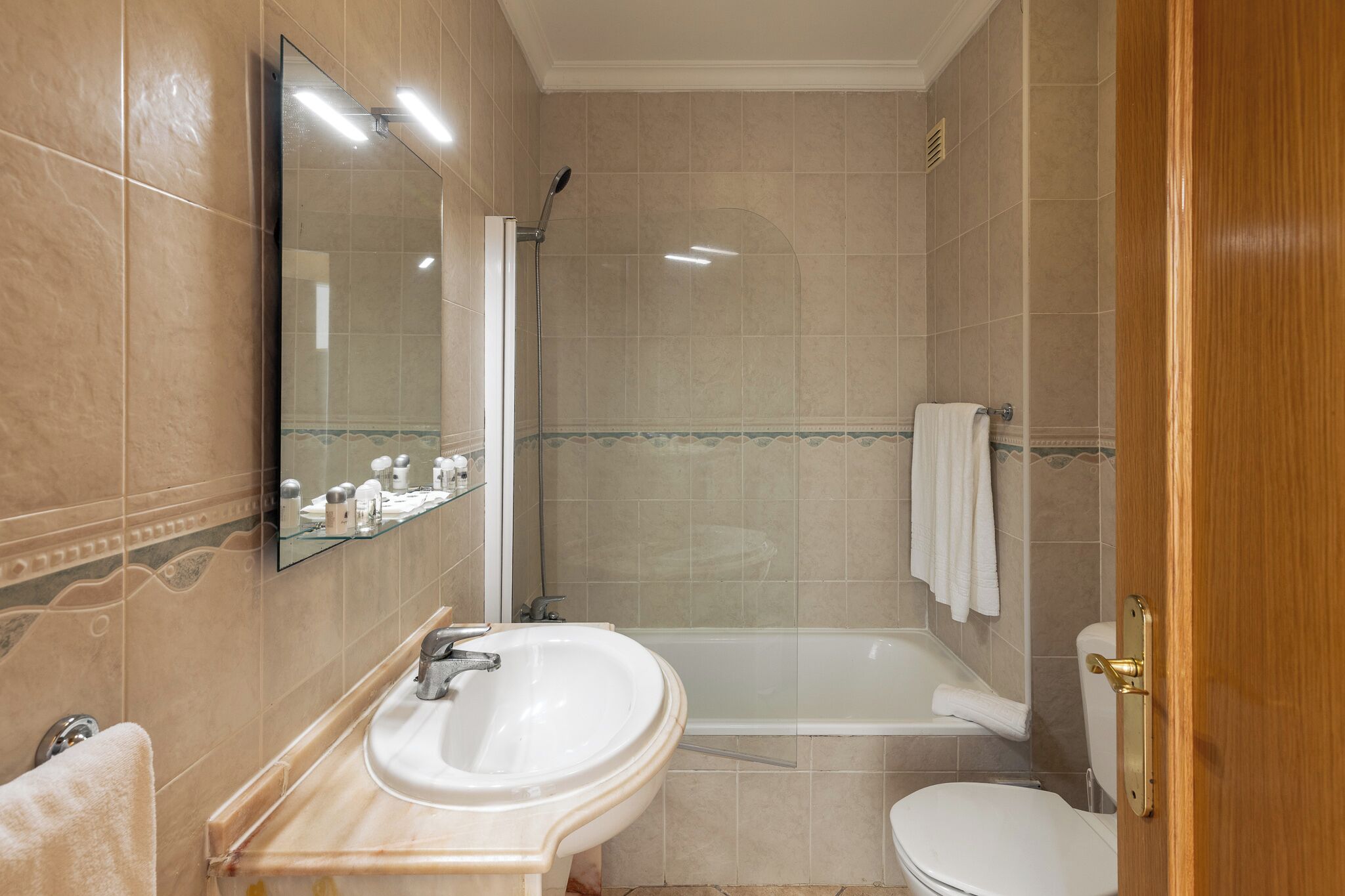 Un baño con lavamanos, espejo, ducha e inodoro.