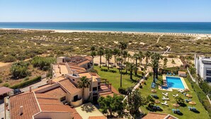A resort with a pool, palm trees, and a beach view. - Praia da Lota Resort – Hotel & Apartments (Vila Real Santo Antonio)