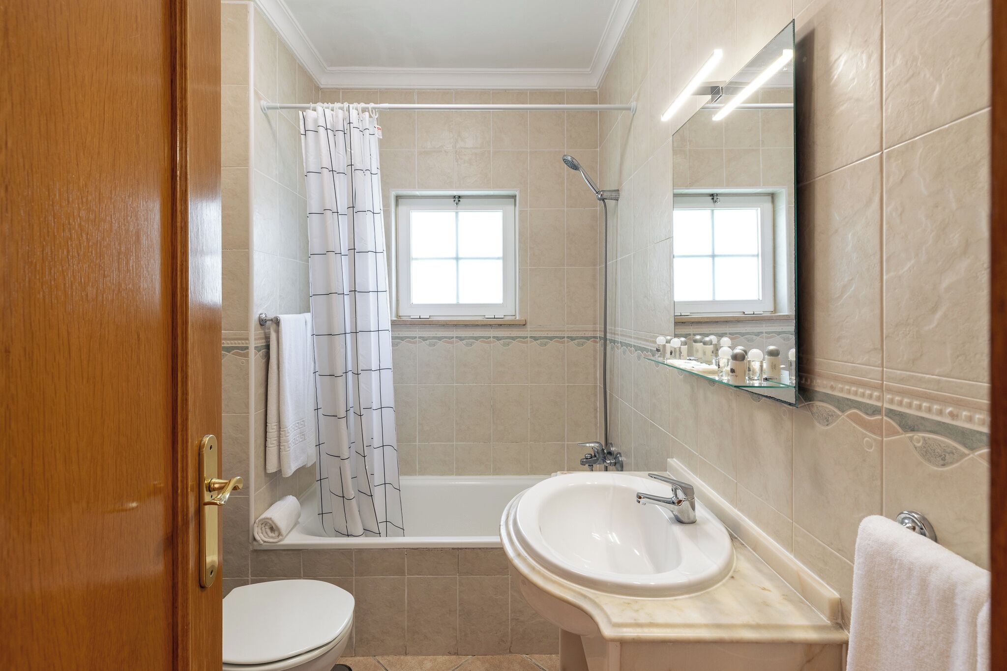 Ein Badezimmer mit einer Badewanne, einem Waschbecken, einer Toilette, einer Dusche und einem Fenster.