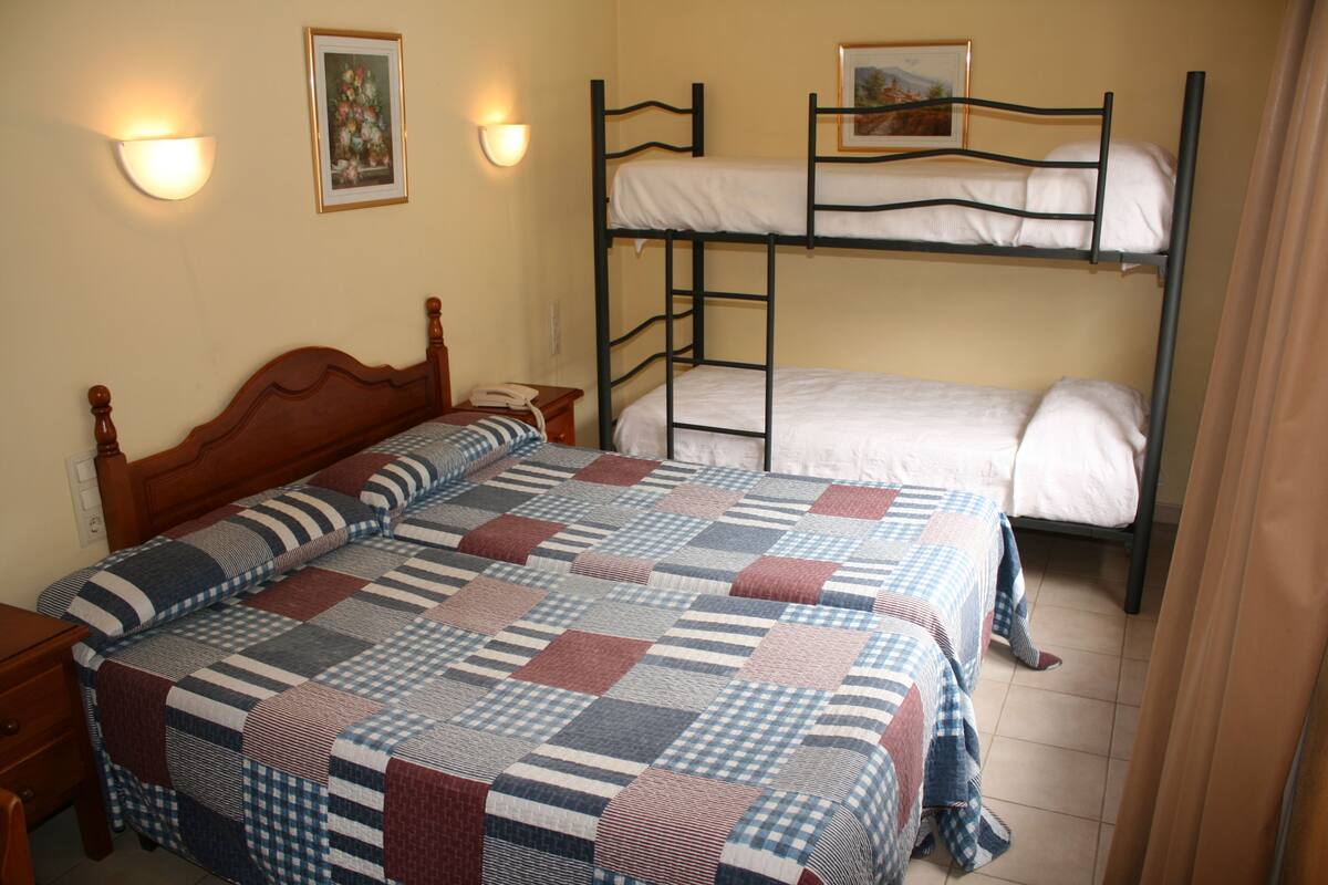 Una habitación con cama de madera, literas y colcha acolchada.