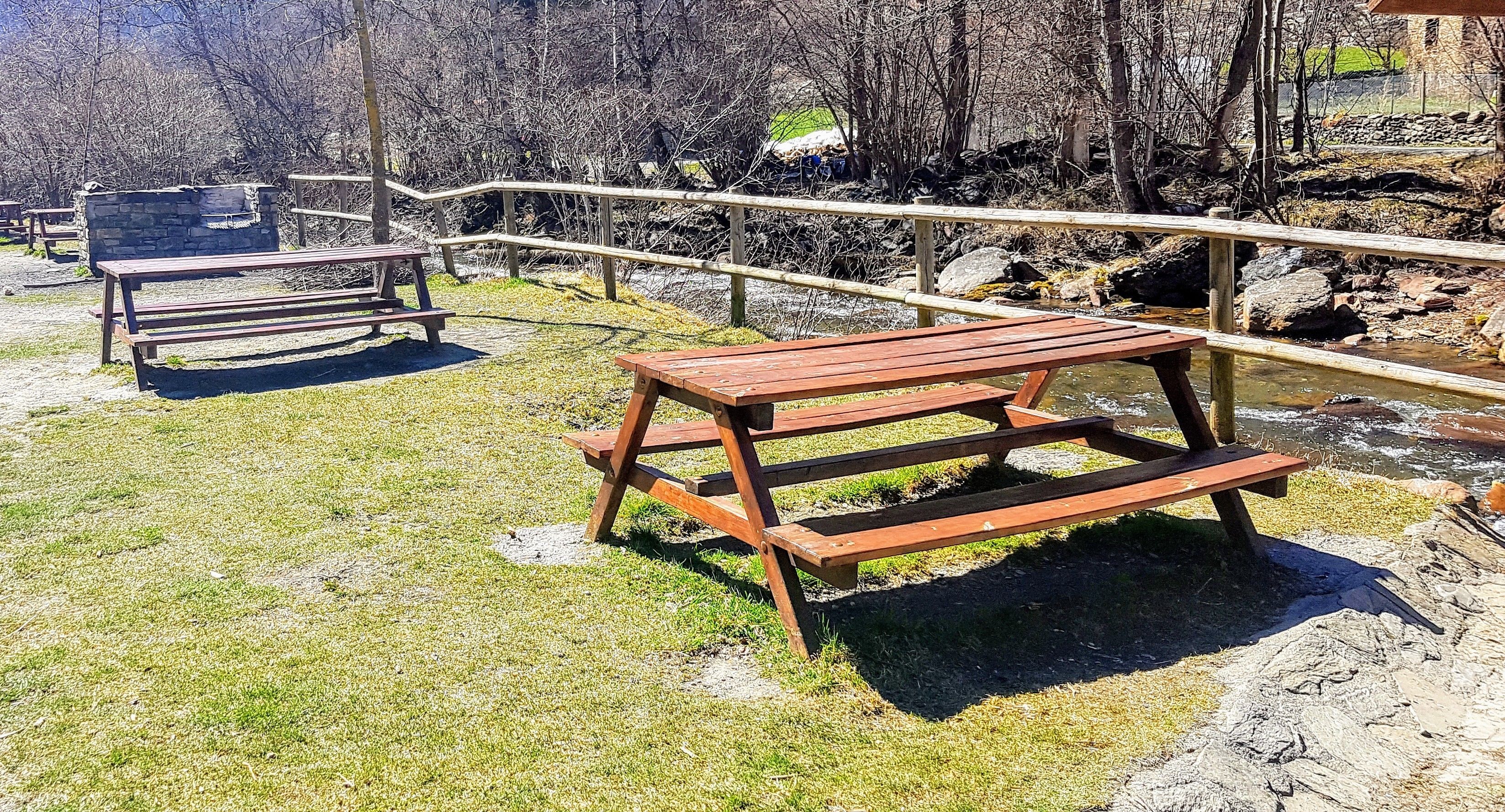 Un área de picnic con bancos de madera y un muro de piedra.