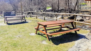 Un área de picnic con bancos de madera y un muro de piedra.