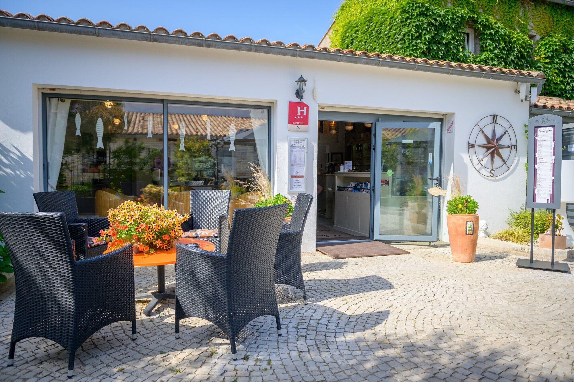 Un restaurante con terraza, entrada por puerta de cristal y un letrero que indica una calificación de 4 estrellas.