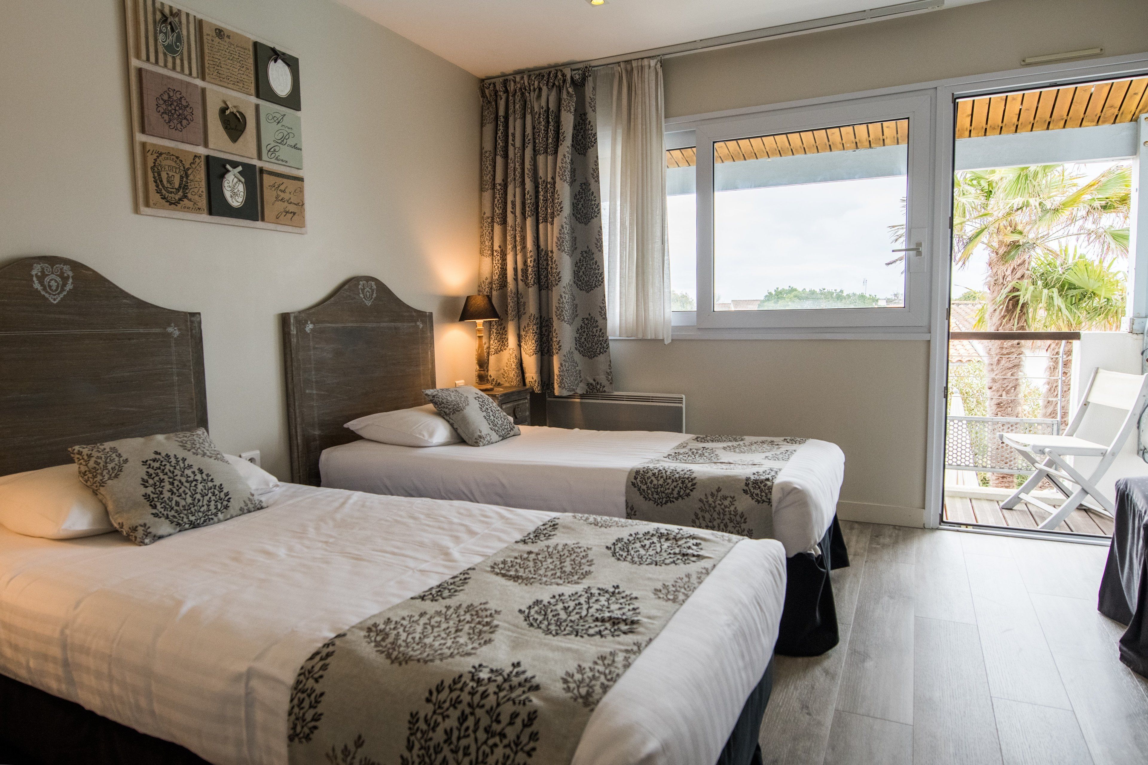 Habitació d'hotel amb dos llits, un balcó amb vistes i una paret amb quadres.