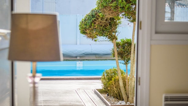 Une chambre avec vue sur une piscine, une lampe et un lit.