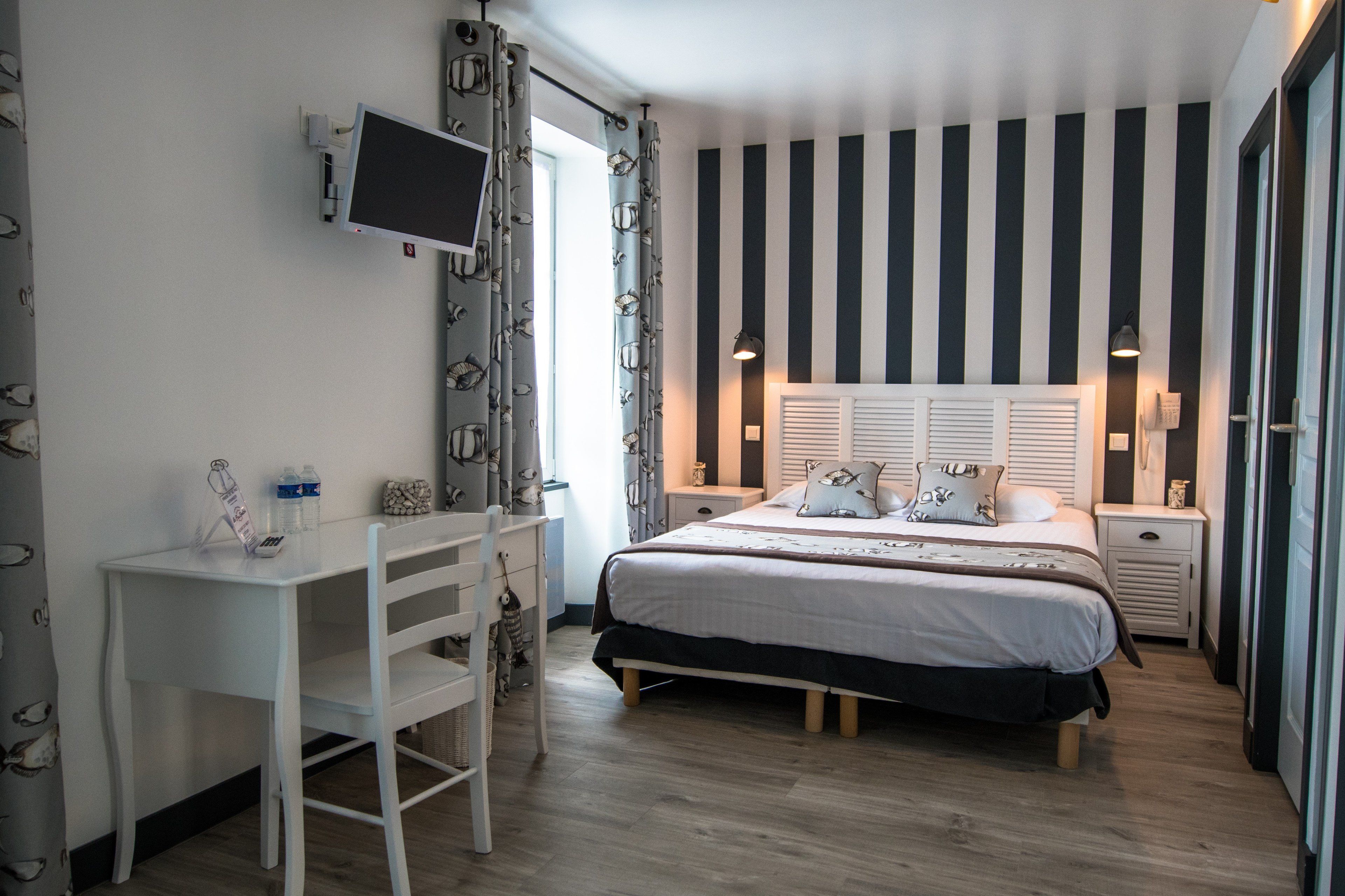 A bedroom with a bed, bedside tables, a desk, and a chair.